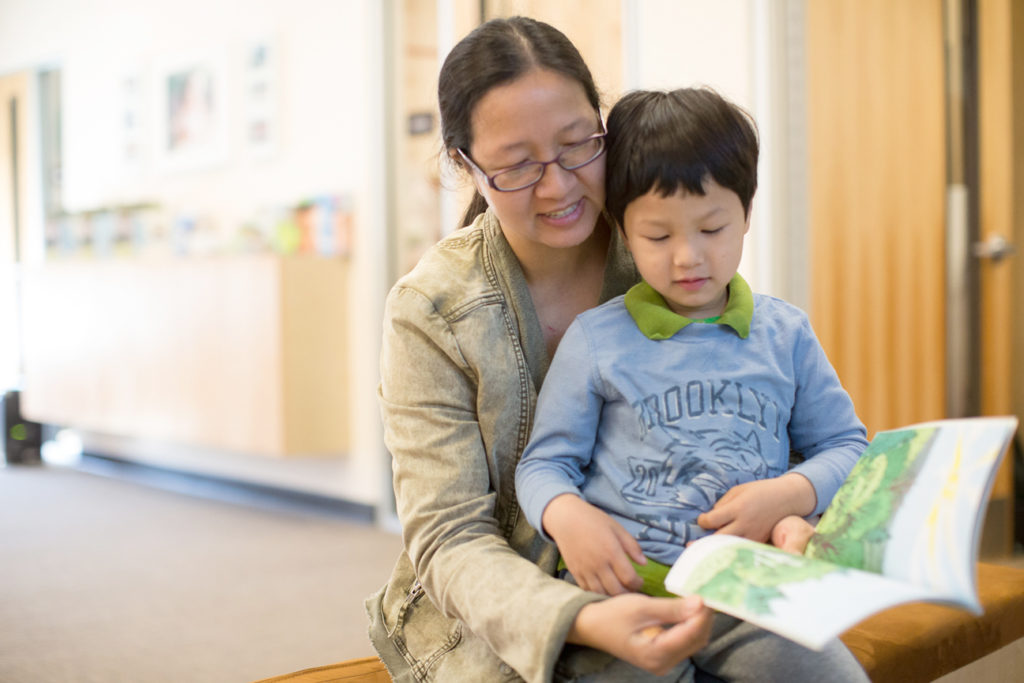 A child and caregiver read a book at a Family Resource Center.